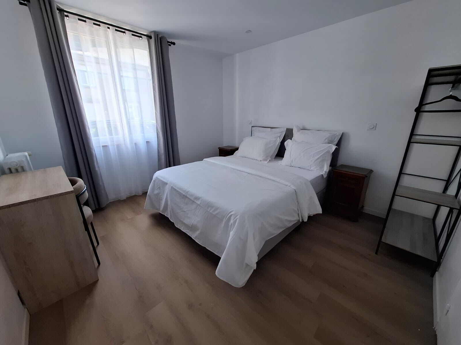 A bedroom with a bed, bedside tables, a desk, and a wardrobe.