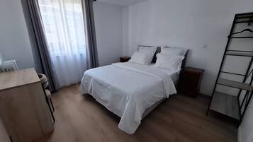 A bedroom with a bed, bedside tables, a desk, and a wardrobe.