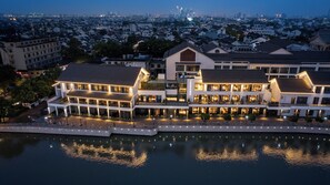 Un hotel frente al agua con varias edificaciones, un muelle y un paisaje urbano al fondo.