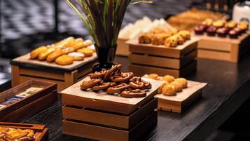 Un tavolo da buffet con diversi prodotti da forno, tra cui pretzel e pasticcini, disposti in scatole di legno.