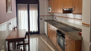 A kitchen with wooden cabinets, a granite countertop, a microwave, and a stove. - Apartamentos Villa de Aínsa (Aínsa)