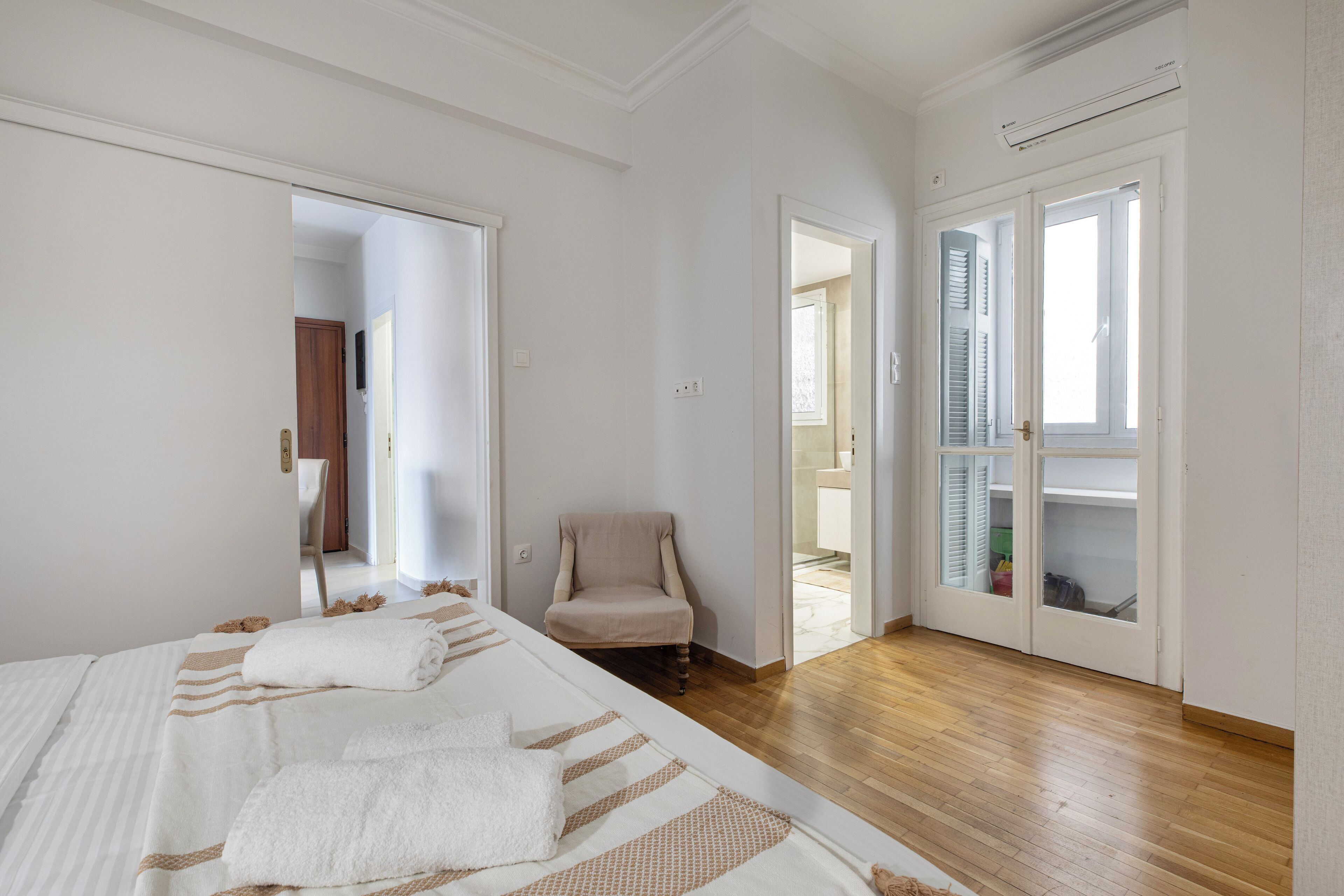 A bedroom with a bed, a chair, and a door leading to a bathroom.