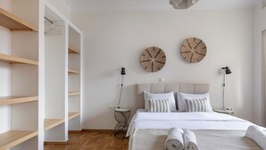 A modern bedroom with a large bed, two bedside lamps, and a herringbone wooden floor. - Attica - Captivating 2-Bedroom Apt & Balcony in Athens (Athens)