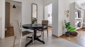 A dining area with a round table, chairs, a potted plant, and a mirror on the wall. - Attica - Captivating 2-Bedroom Apt & Balcony in Athens (Athens)