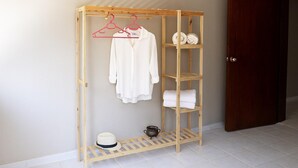 Un armario de madera con zona para colgar y estantes, un sombrero y una maceta en el suelo.