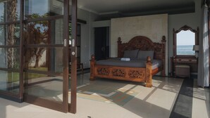 Un dormitorio con una cama grande, un ventanal corredero que da a un balcón y vistas al mar.