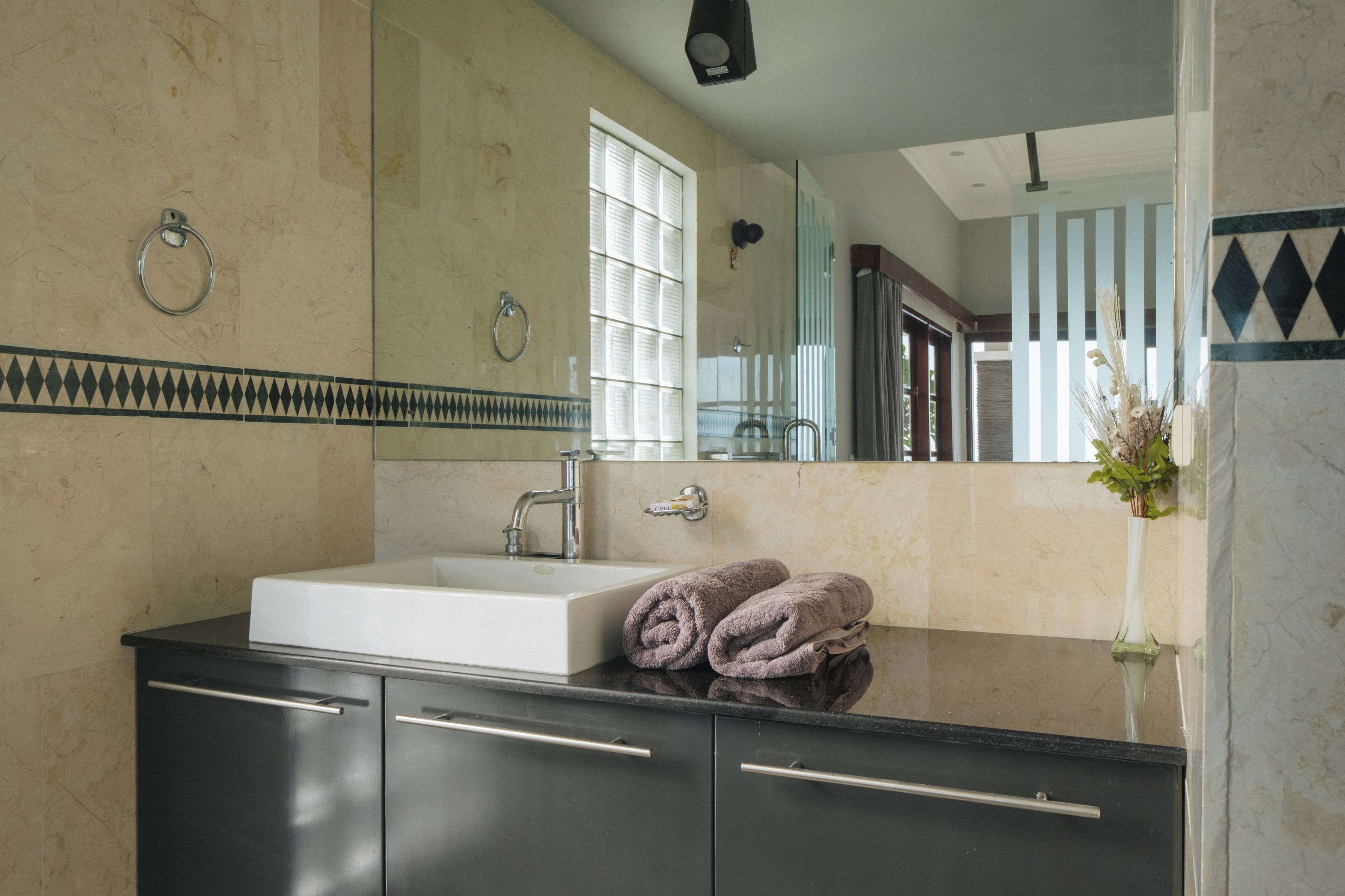 A bathroom with a sink, mirror, and towels.