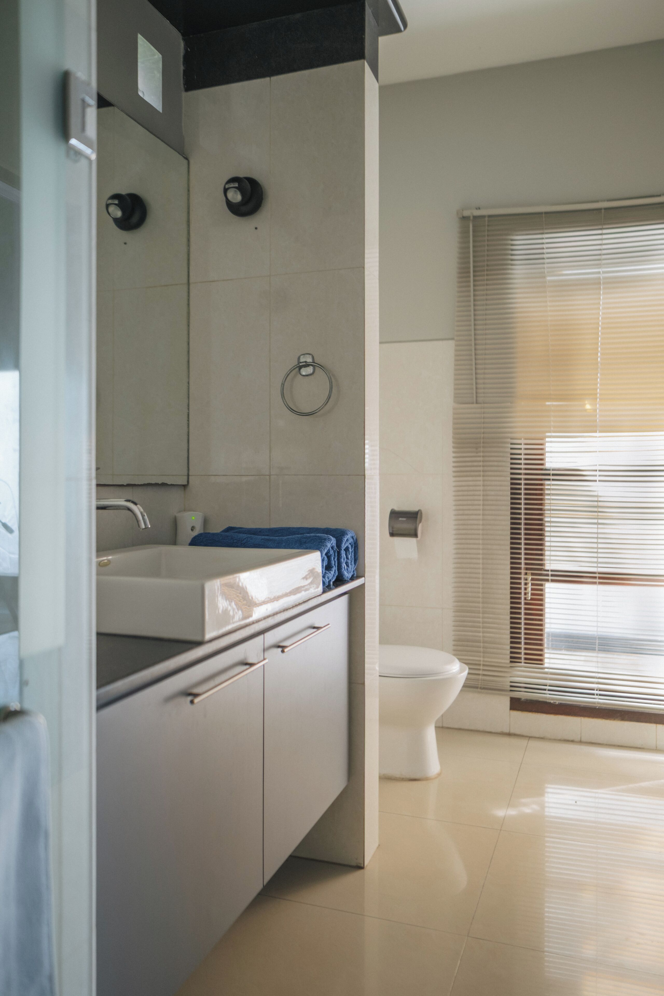A modern bathroom with a white sink, mirror, and toilet.