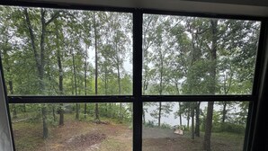 A window with a view of a forested area and a body of water.