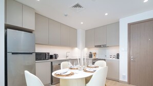 Une cuisine moderne dotée d’un îlot central, de chaises blanches et d’une table à manger dressée pour quatre personnes.