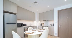 Une cuisine moderne dotée d’un îlot central, de chaises blanches et d’une table à manger dressée pour quatre personnes.