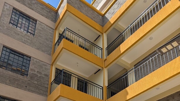 A multi-story building with balconies, a covered courtyard, and a stairway. - Live Light, Live Right.Fully-Furnished Studio Apartment in Machakos! (Machakos)