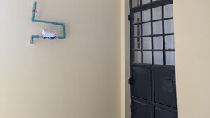 A room with a beige wall, a black door with a grid pattern, and a white ceiling with a recessed light fixture. - Live Light, Live Right.Fully-Furnished Studio Apartment in Machakos! (Machakos)