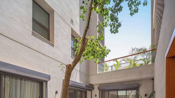 Un patio exterior moderno con una hamaca, sillas de mimbre y plantas en macetas.