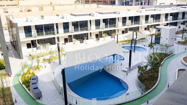 A modern multi-story building with a rooftop pool and surrounding greenery. - Bloomfields Homey Stu The Gate Masdar  (Abu Dhabi)