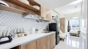 A modern kitchen with wooden cabinets, a white countertop, and a hexagonal tile backsplash. - Modern Nordic Studio with Balcony and Pool in Primeworld District Near Airport (Lapu-Lapu)