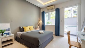 Una habitación de hotel con cama, escritorio, silla, lámpara y equipo de aire acondicionado.