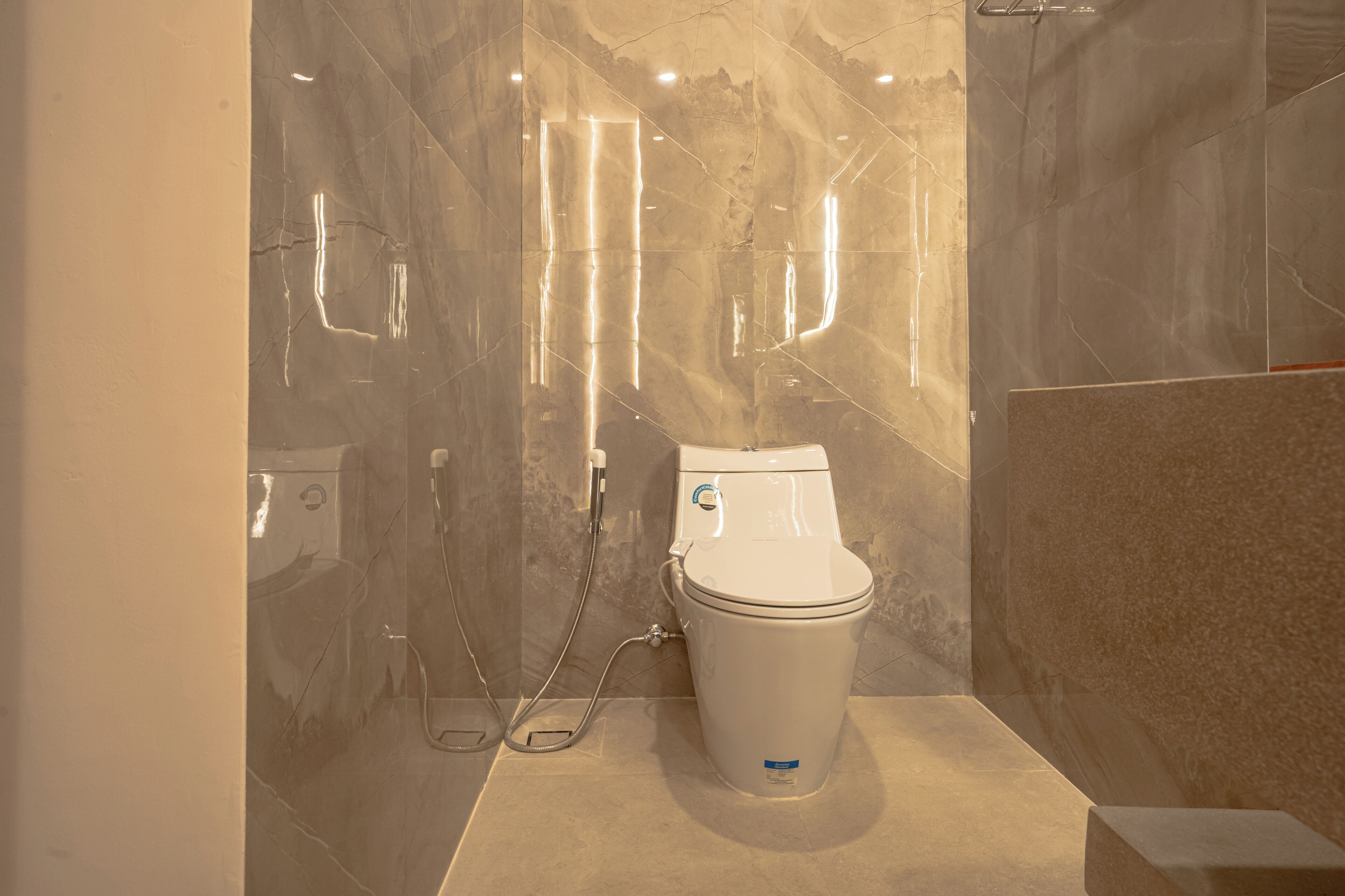 Ein modernes Badezimmer mit Toilette, Dusche und Marmorwänden.