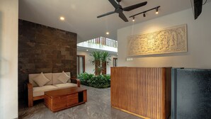 Una sala de estar moderna con una pared de piedra, una mesa de centro de madera, un sofá, un ventilador de techo y una obra de arte grande en la pared.