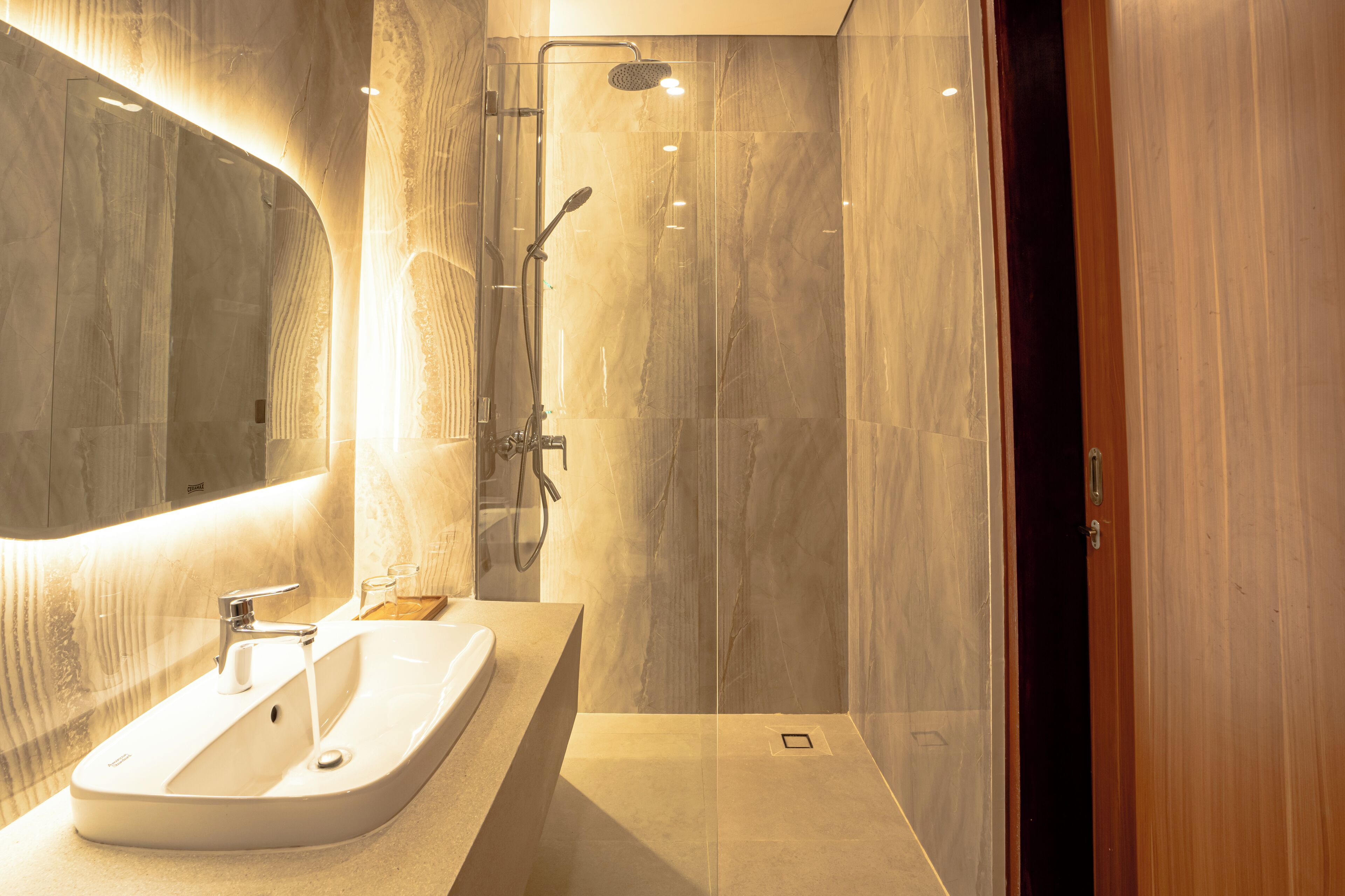Une salle de bain moderne avec un grand miroir, un lavabo et un espace douche.