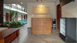 Un moderno vestíbulo de hotel con piscina, un banco de madera, un refrigerador y un ventilador de techo.