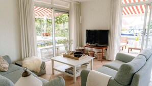 A living room with a sofa, a coffee table, a TV, and a view of the outdoors. - Nice holiday home on the water in Grou (Grou)