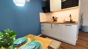 A compact kitchen with white cabinets, a black microwave, and a wooden countertop.