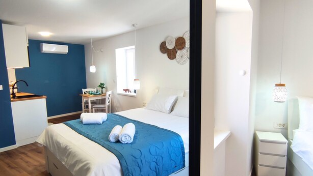 A modern bedroom with a bed, bedside tables, a desk, and a chair.