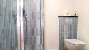 A bathroom with a glass-enclosed shower, a toilet, and a sink.