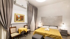 A hotel room with a bed, a desk, a chair, a table, and a painting on the wall. - BB Melody House (Florence)