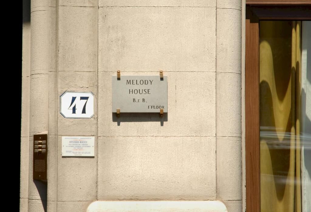 A building with a sign indicating "Melody House B.B. 1st Floor" and a smaller sign for "Studio Ricci".