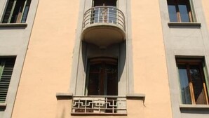 A multi-story building with a central balcony, a wooden door, and a small sign above the entrance. - BB Melody House (Florence)