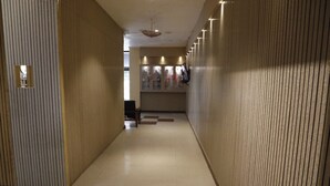 A hallway with wooden paneling, a tiled floor, and a reception area with a counter and framed pictures.