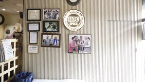A reception area with a wooden panel wall, framed certificates, a clock, and a 'HOH SPICE' sign.