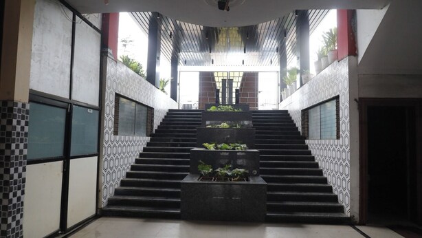 A staircase with a geometric patterned wall on one side and a tiled wall on the other, leading to a bright interior space.