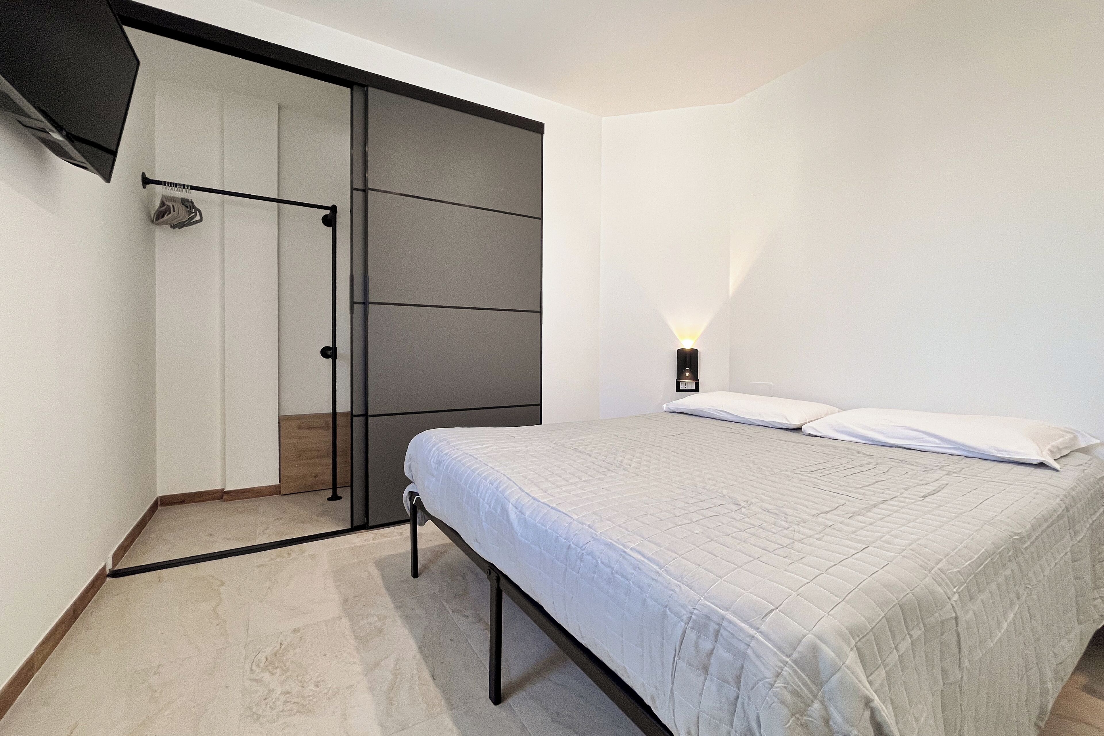 Una camera da letto con un letto, un armadio e un comodino con una lampada.