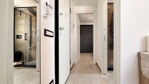 A modern hallway with a glass shower, a door with a phone, and a towel rack. - Tiny Loft Skydeck (Civitavecchia)