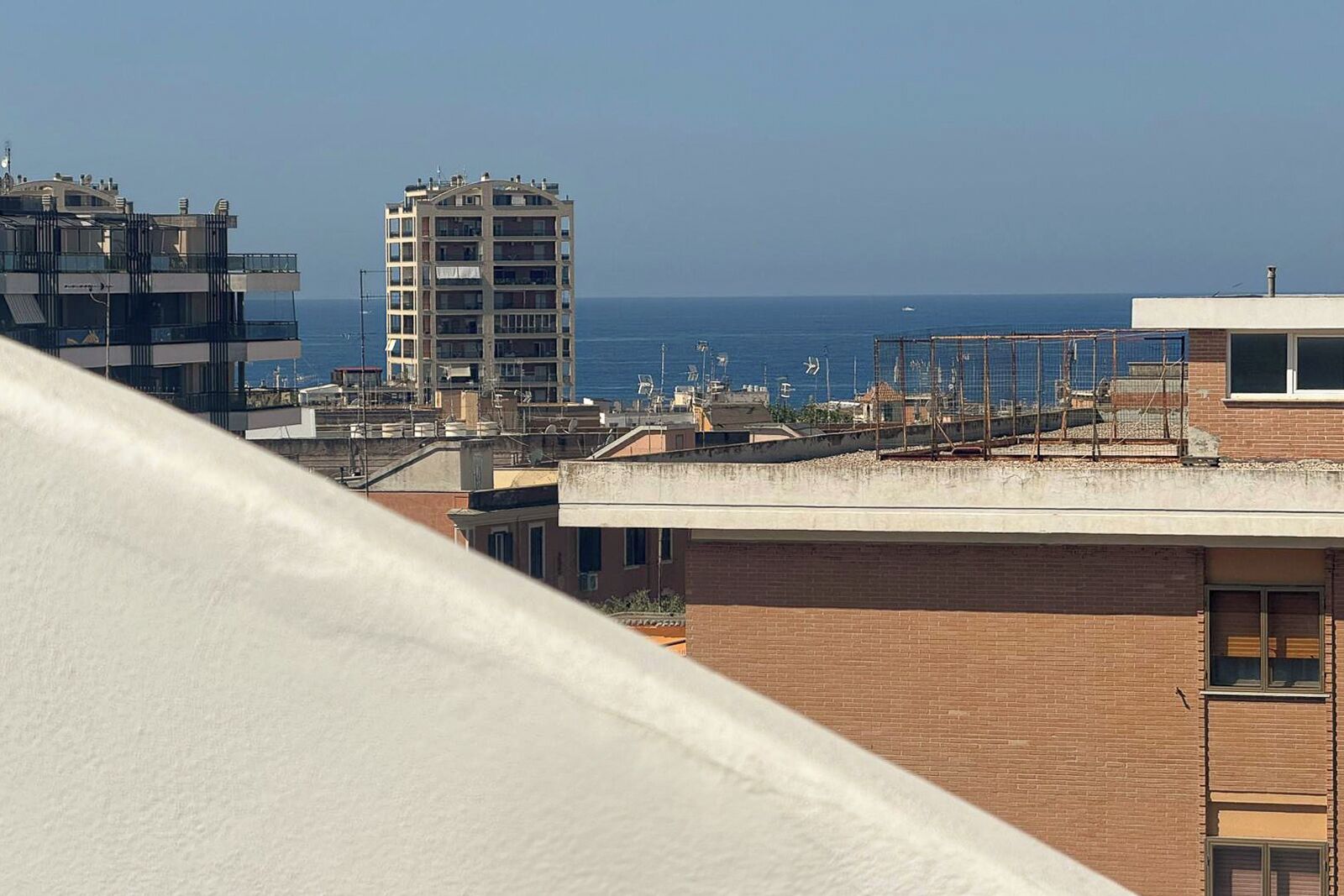 Eine Küstenstadtlandschaft mit einem markanten mehrstöckigen Gebäude und freiem Blick auf das Meer.