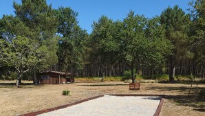 A dry grass field with a gravel area and a wooden structure in the background. - Relaxation tent (Callen)