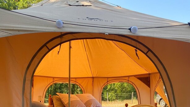 A tent with a bed inside, featuring a canopy and a view of the outdoors. - Relaxation tent (Callen)