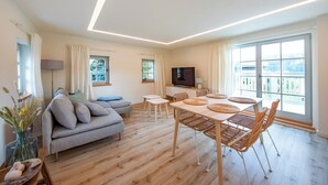 A modern living room with a sofa, TV, dining table, and chairs. - Fantastic guest house on the Elbe cycle path and Bastei (Rathen)