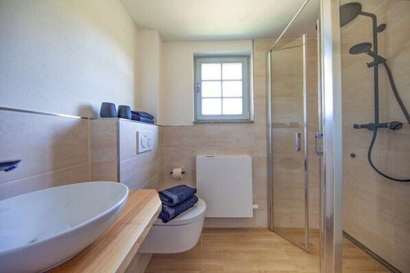 Un baño moderno con un lavamanos grande, inodoro y ducha.