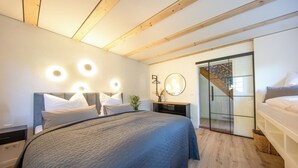 A modern bedroom with a large bed, bedside tables, a mirror, and a sliding glass door leading to a balcony. - Fantastic guest house on the Elbe cycle path and Bastei (Rathen)