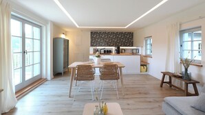 A modern kitchen with a dining area, large windows, and a cozy seating area with a sofa and a small table. - Fantastic guest house on the Elbe cycle path and Bastei (Rathen)