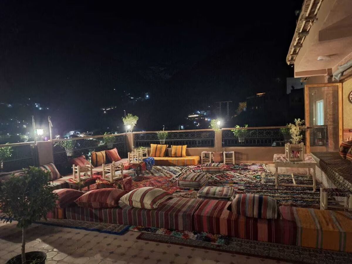 Un espacio de estar al aire libre con varios sofás y sillones, una alfombra estampada y una mesita con una planta.