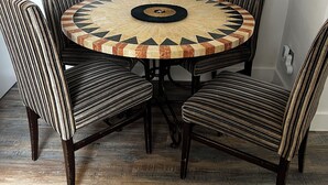 A round dining table with a patterned center, surrounded by six striped chairs. - Southend luxe retreat (Southend-on-Sea)