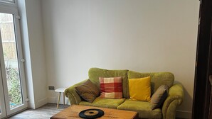 A living room with a green sofa, a wooden coffee table, and a view through a sliding glass door. - Southend luxe retreat (Southend-on-Sea)