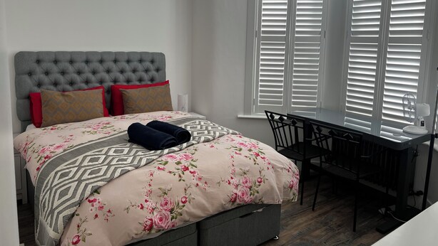 A bedroom with a bed, a desk, and a window with blinds. - Southend luxe retreat (Southend-on-Sea)