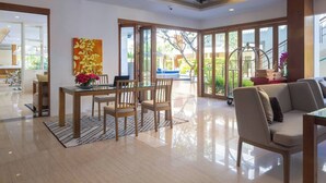 A spacious living area with a glass door leading to a balcony, a dining table with chairs, and a sofa. - VIP Dream Suite Residence Krabi (Krabi)