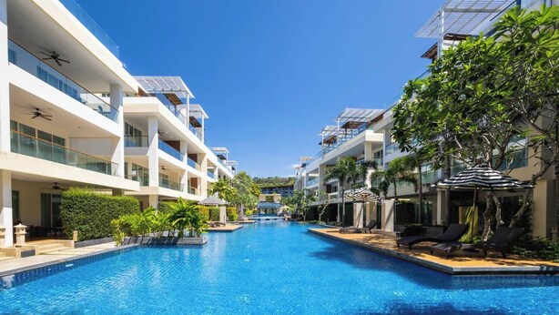 A modern hotel with a central swimming pool, multiple balconies, and lush greenery. - VIP Dream Suite Residence Krabi (Krabi)